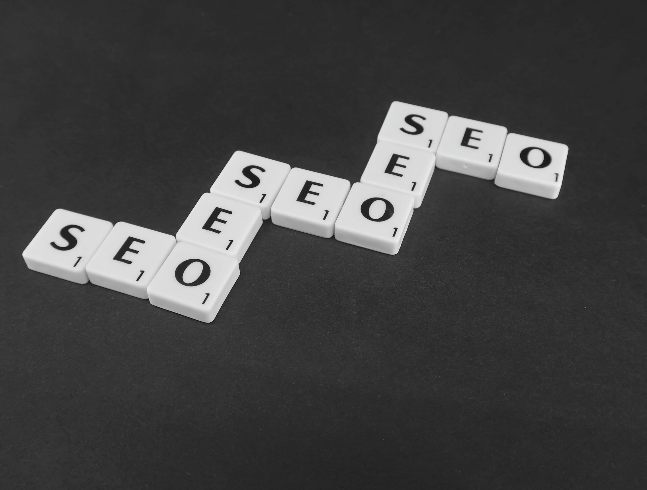 SEO spelled repeatedly in white scrabble tiles on a black background, representing comparing SEO and link building providers